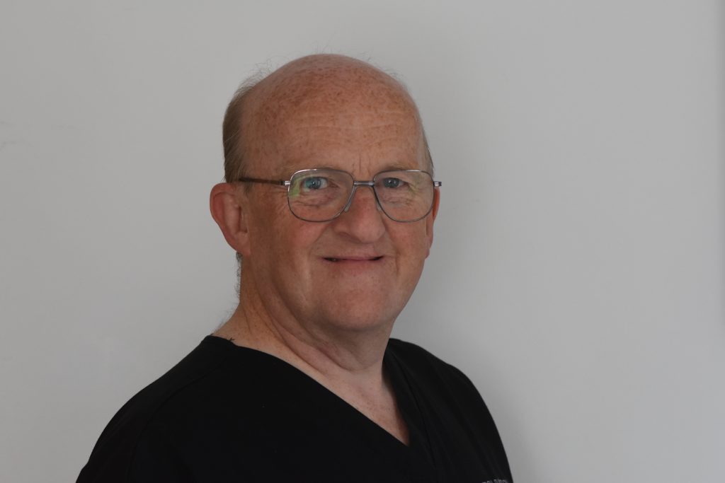 Paul Begley, Dutchbarton Dentist, smiling at the camera whilst wearing scrubs