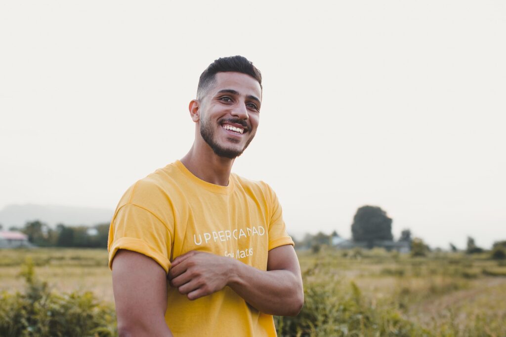 Man in yellow t-shirt smiling outside